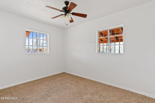 empty room with carpet flooring, baseboards, and a ceiling fan