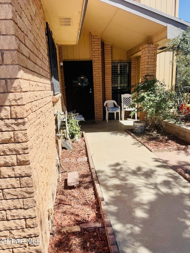 property entrance with brick siding and visible vents