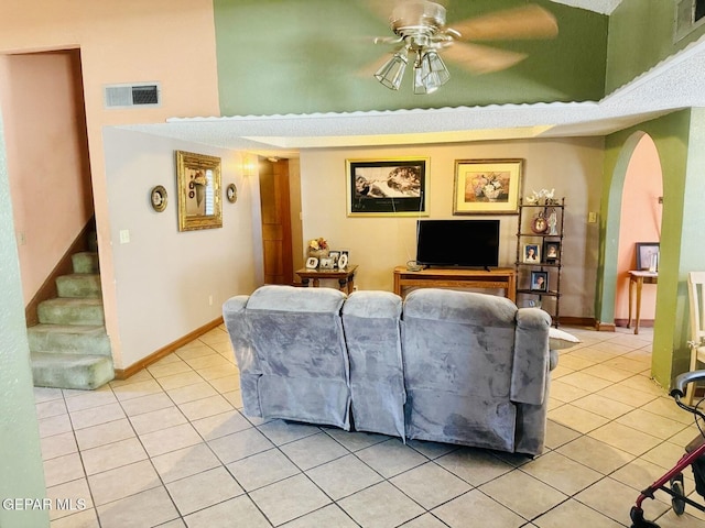 living area with a ceiling fan, arched walkways, light tile patterned floors, and visible vents