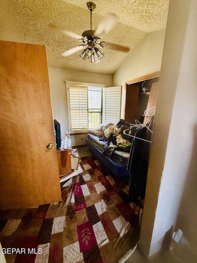 bedroom featuring a closet, a textured ceiling, lofted ceiling, and ceiling fan