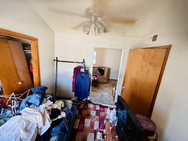 carpeted bedroom with lofted ceiling, a textured ceiling, ceiling fan, and visible vents