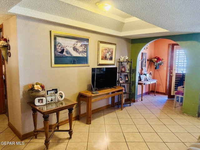 interior space with light tile patterned floors, baseboards, and a textured ceiling