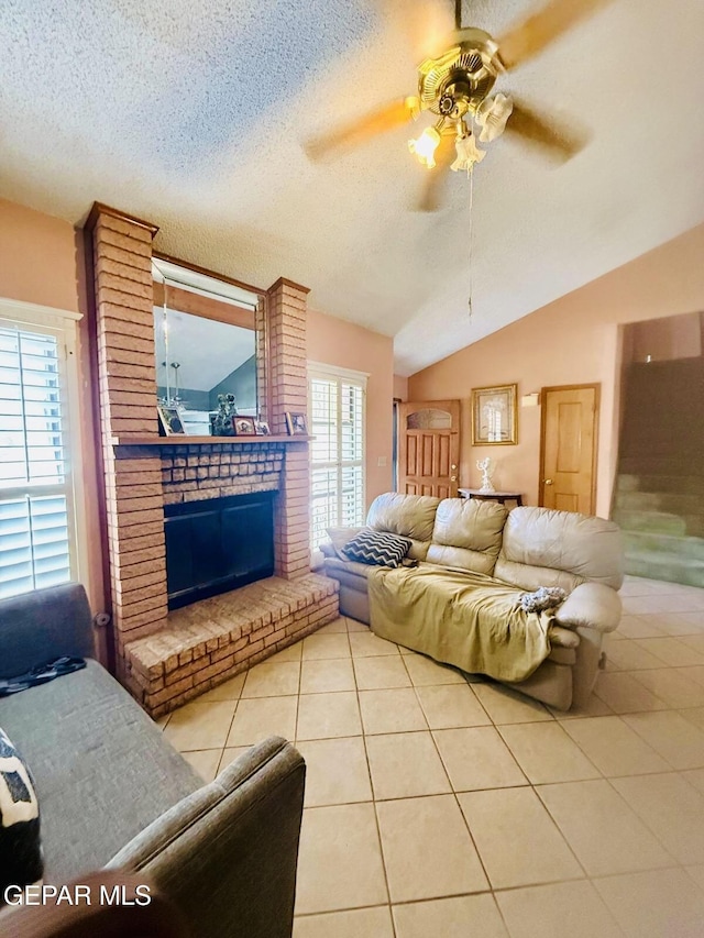 living area with lofted ceiling, a textured ceiling, a brick fireplace, a ceiling fan, and light tile patterned floors
