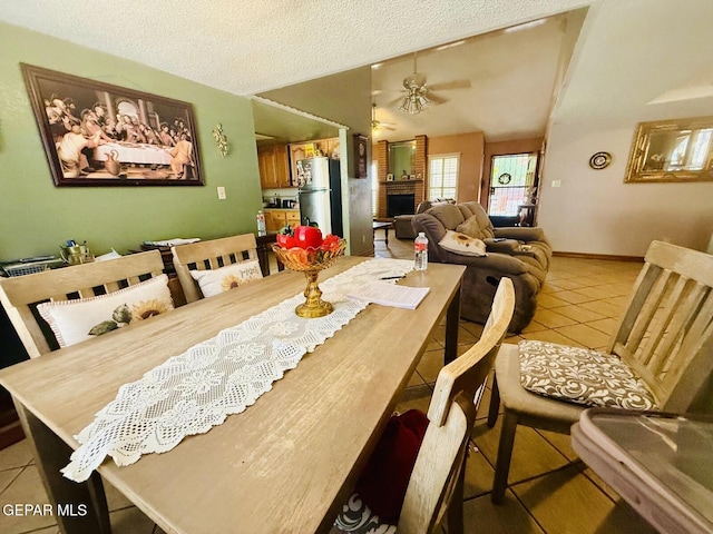 dining room featuring light tile patterned flooring, a textured ceiling, a fireplace, and a ceiling fan