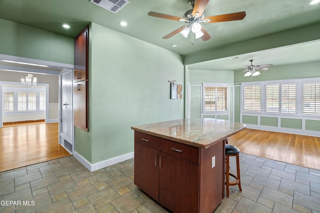 3020 Wheeling Ave, El Paso, TX 79930 - kitchen with ceiling fan, stone finish floors, baseboards, a kitchen bar, and a chandelier