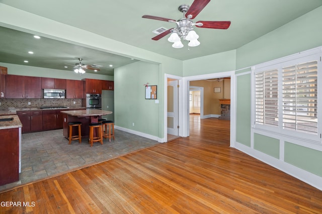 3020 Wheeling Ave, El Paso, TX 79930 - kitchen with stainless steel microwave, ceiling fan, a center island, backsplash, and baseboards