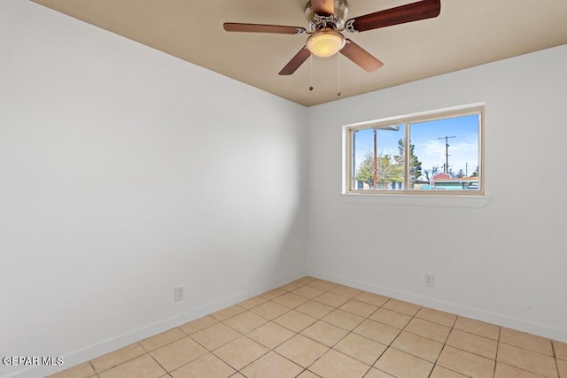 empty room featuring baseboards, ceiling fan, and light tile patterned floors