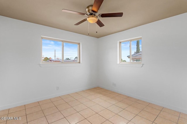 spare room featuring plenty of natural light, a ceiling fan, and baseboards
