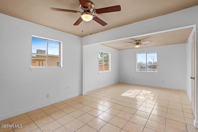 empty room featuring a ceiling fan, light tile patterned flooring, and baseboards