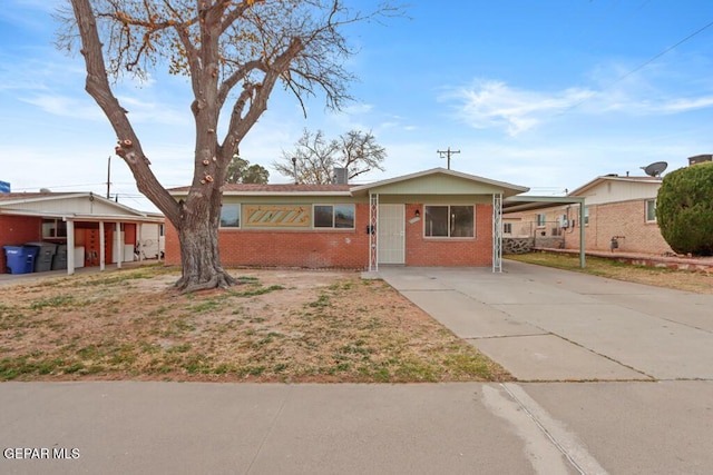 single story home with brick siding, concrete driveway, and a carport