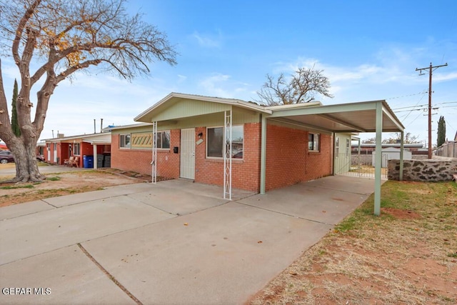 view of front of home with driveway, brick siding, and an attached carport