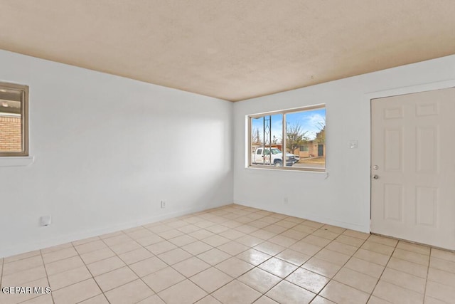spare room featuring light tile patterned floors and baseboards