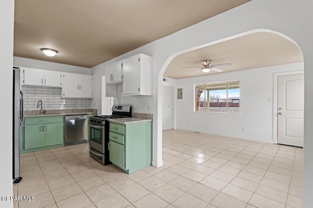 kitchen featuring appliances with stainless steel finishes, arched walkways, a sink, a ceiling fan, and white cabinets
