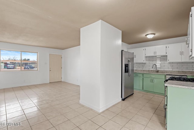 kitchen with appliances with stainless steel finishes, light tile patterned flooring, backsplash, and a sink