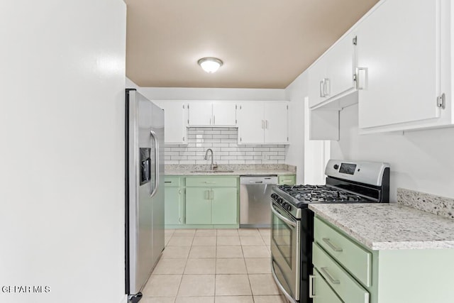 kitchen featuring stainless steel appliances, a sink, light countertops, tasteful backsplash, and light tile patterned floors
