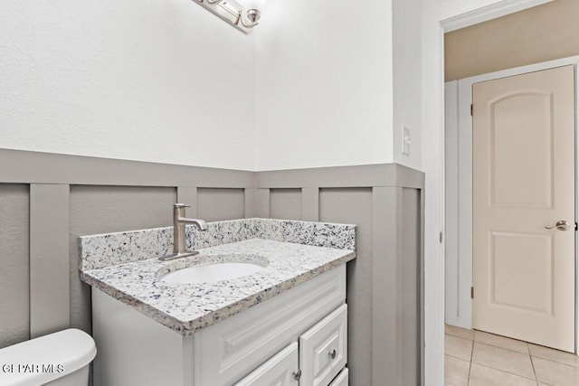 bathroom featuring vanity, tile patterned floors, toilet, and wainscoting