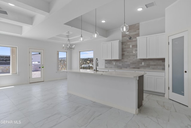 kitchen with white cabinetry, marble finish floor, decorative backsplash, and a sink