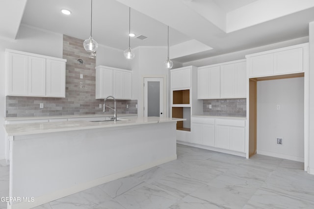 kitchen with backsplash, white cabinetry, marble finish floor, and a sink