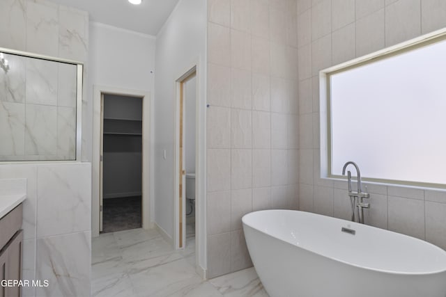 full bath featuring tile walls, marble finish floor, vanity, a walk in shower, and a freestanding tub