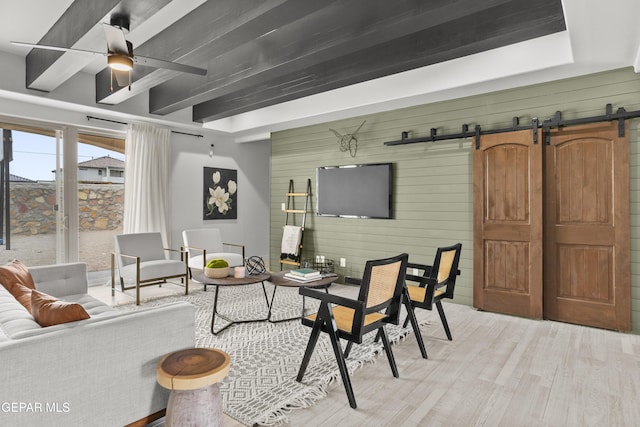 13352 Eton Ct, El Paso, TX 79928 - living room featuring a barn door, light wood-style floors, a ceiling fan, beamed ceiling, and wood walls