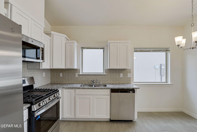 14296 Chris Zingo Ln, El Paso, TX 79928 - kitchen with appliances with stainless steel finishes, a chandelier, decorative backsplash, and white cabinetry