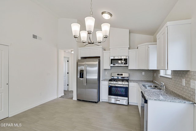 14296 Chris Zingo Ln, El Paso, TX 79928 - kitchen featuring appliances with stainless steel finishes, a sink, a chandelier, tasteful backsplash, and light stone countertops