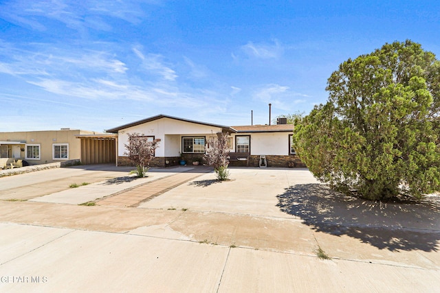 single story home featuring stone siding, stucco siding, and driveway