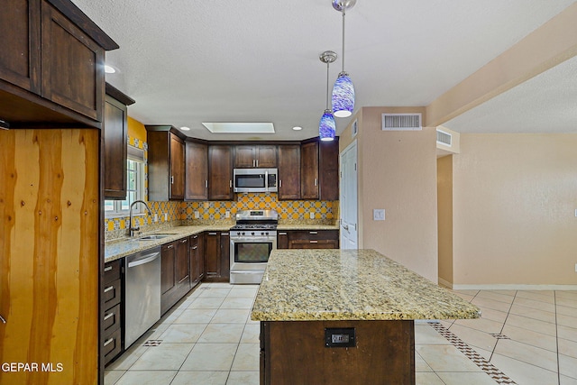 kitchen with stainless steel appliances, light tile patterned flooring, backsplash, a sink, and light stone countertops