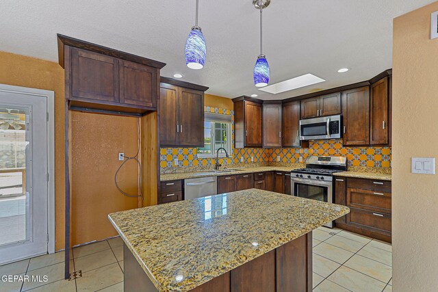 kitchen with stainless steel appliances, a sink, backsplash, light tile patterned flooring, and a textured ceiling