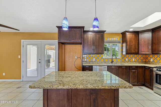 kitchen featuring a sink, stainless steel appliances, a textured ceiling, decorative backsplash, and light tile patterned floors