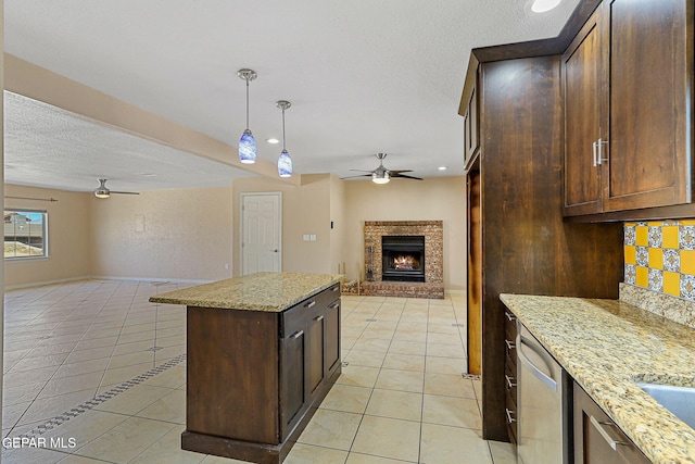 kitchen featuring ceiling fan, open floor plan, light tile patterned flooring, backsplash, and a brick fireplace