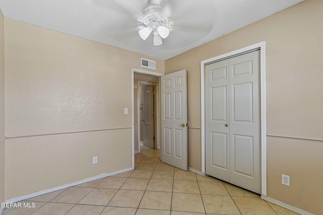 unfurnished bedroom featuring light tile patterned flooring, baseboards, a closet, and ceiling fan