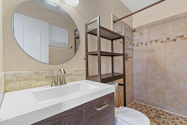 bathroom featuring tiled shower, vanity, toilet, and tile walls
