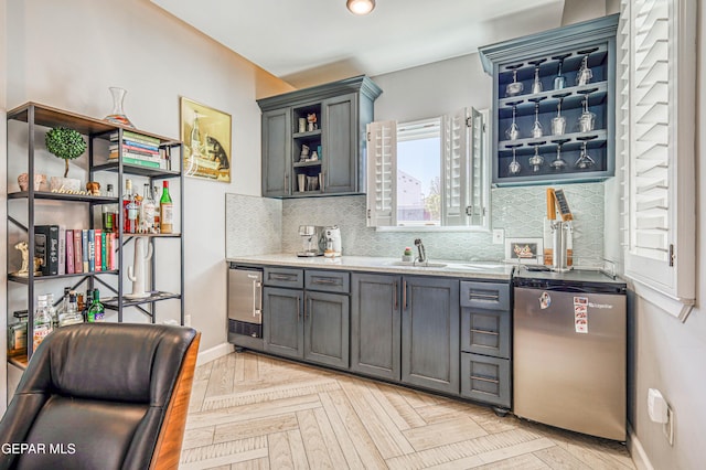 bar area with dishwasher, a sink, backsplash, and baseboards