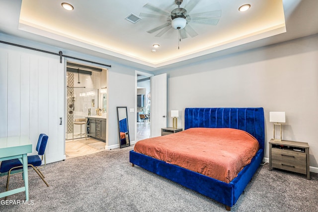 carpeted bedroom with a tray ceiling, recessed lighting, ensuite bath, and baseboards