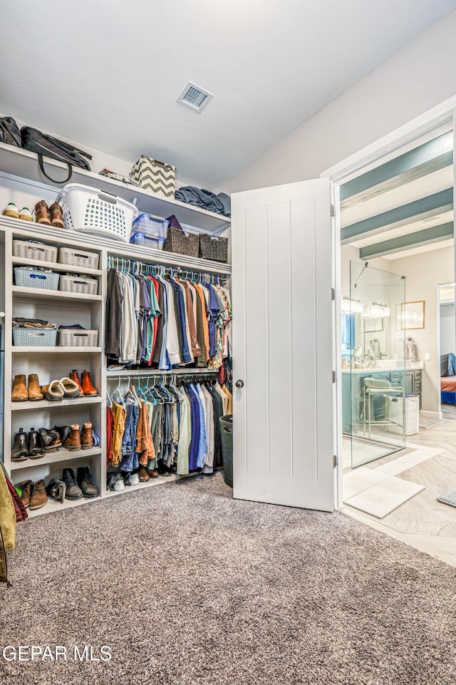 walk in closet featuring carpet floors and vaulted ceiling