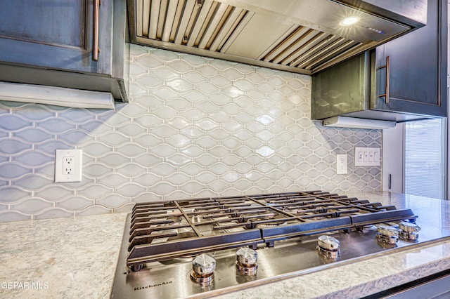 kitchen featuring custom range hood, stainless steel gas cooktop, light countertops, and backsplash