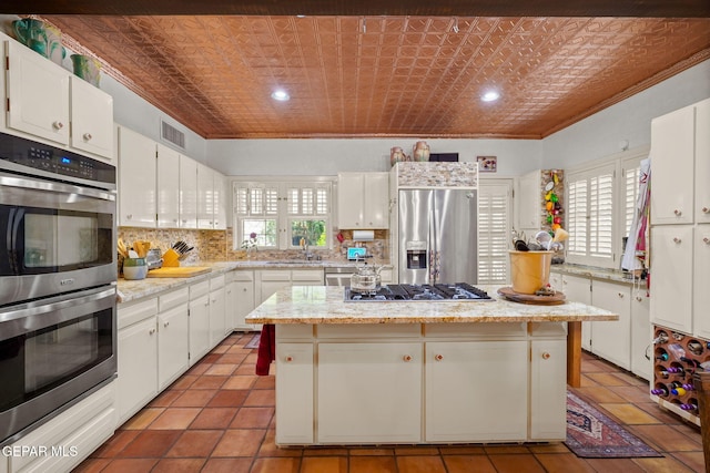 kitchen with appliances with stainless steel finishes, plenty of natural light, crown molding, tasteful backsplash, and a center island