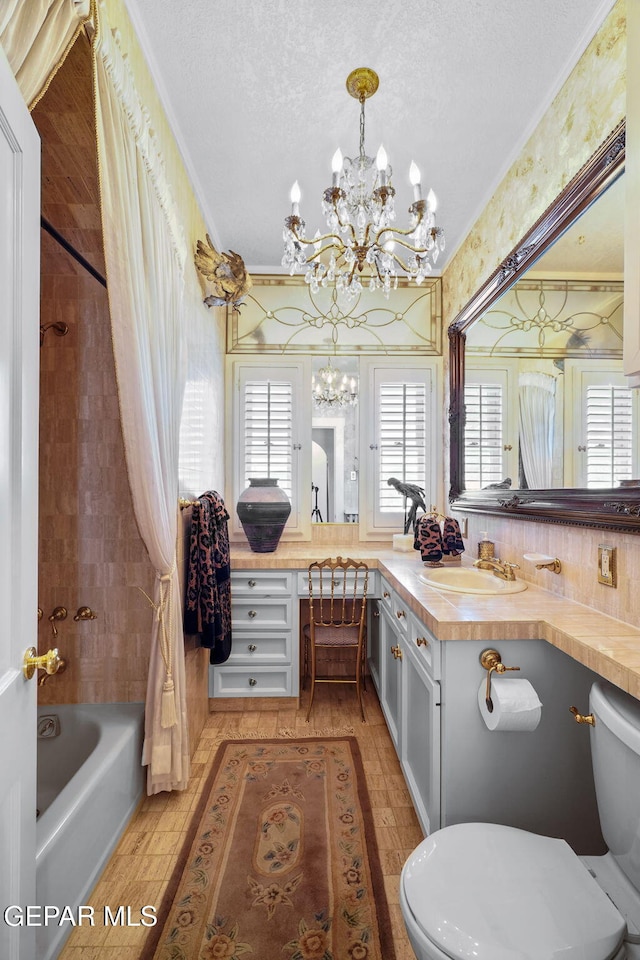 full bathroom featuring a chandelier, toilet,  shower combination, ornamental molding, and vanity