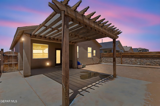 patio terrace at dusk with a pergola and fence