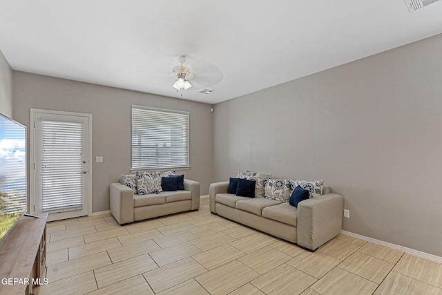 living area featuring a ceiling fan, visible vents, baseboards, and wood tiled floor