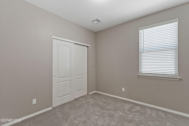 unfurnished bedroom featuring baseboards, a closet, visible vents, and carpet floors