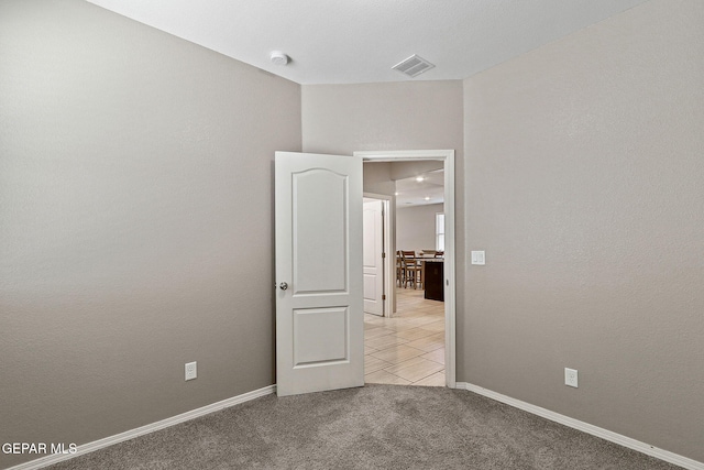 spare room with light carpet, baseboards, and visible vents