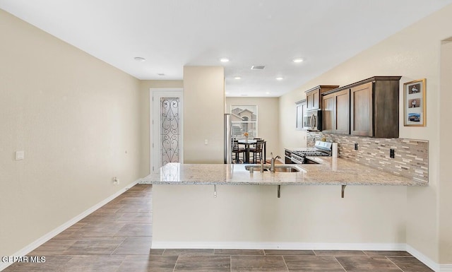 14920 Tierra Fortaleza Ave, El Paso, TX 79938 - kitchen featuring light stone countertops, a sink, a kitchen bar, a peninsula, and stainless steel appliances