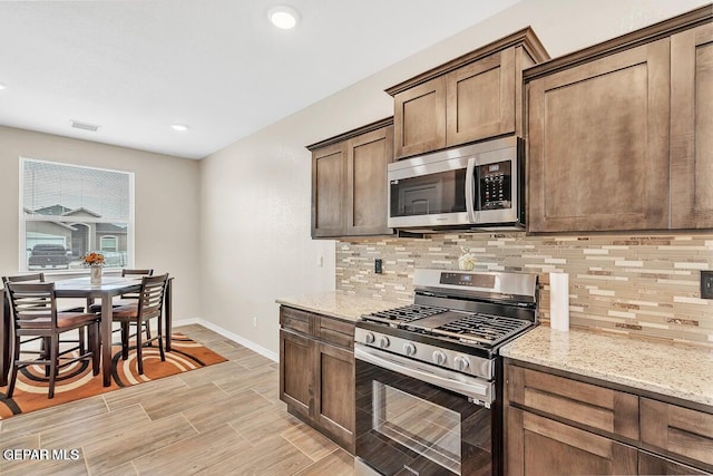 14920 Tierra Fortaleza Ave, El Paso, TX 79938 - kitchen with baseboards, stainless steel appliances, tasteful backsplash, and light stone countertops
