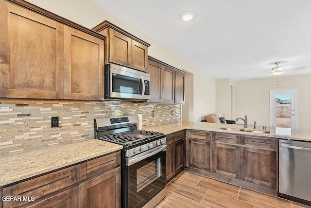14920 Tierra Fortaleza Ave, El Paso, TX 79938 - kitchen featuring a sink, stainless steel appliances, ceiling fan, backsplash, and light stone countertops