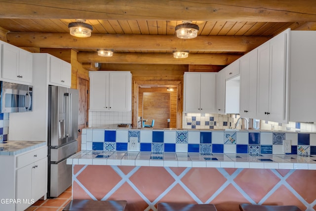 2 Scenic Ridge Rd N, Alpine, TX 99999 - kitchen with appliances with stainless steel finishes, tasteful backsplash, white cabinetry, tile countertops, and beam ceiling