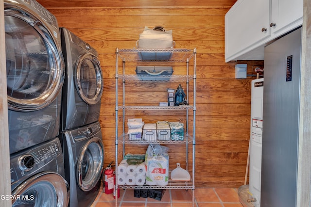 2 Scenic Ridge Rd N, Alpine, TX 99999 - laundry area featuring stacked washer and clothes dryer, cabinet space, tile patterned flooring, wood walls, and water heater