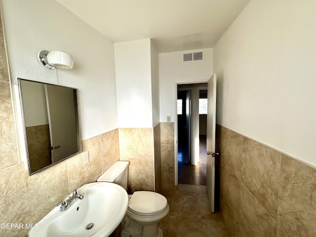 45 S Boone St, El Paso, TX 79905 - half bathroom with tile walls, a wainscoted wall, visible vents, and a sink