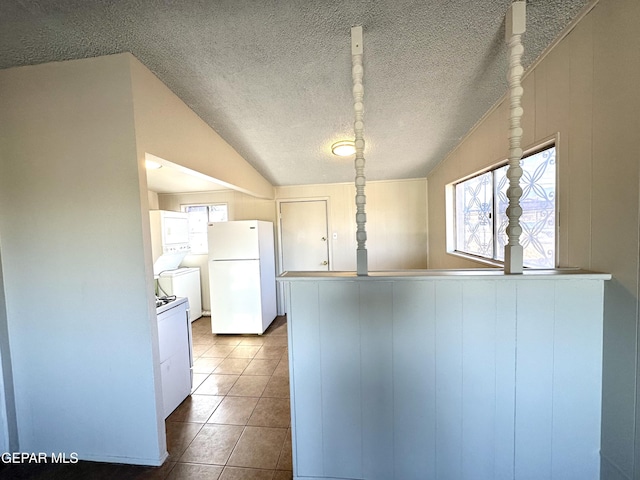 45 S Boone St, El Paso, TX 79905 - kitchen featuring a peninsula, lofted ceiling, white appliances, a textured ceiling, and dark tile patterned flooring